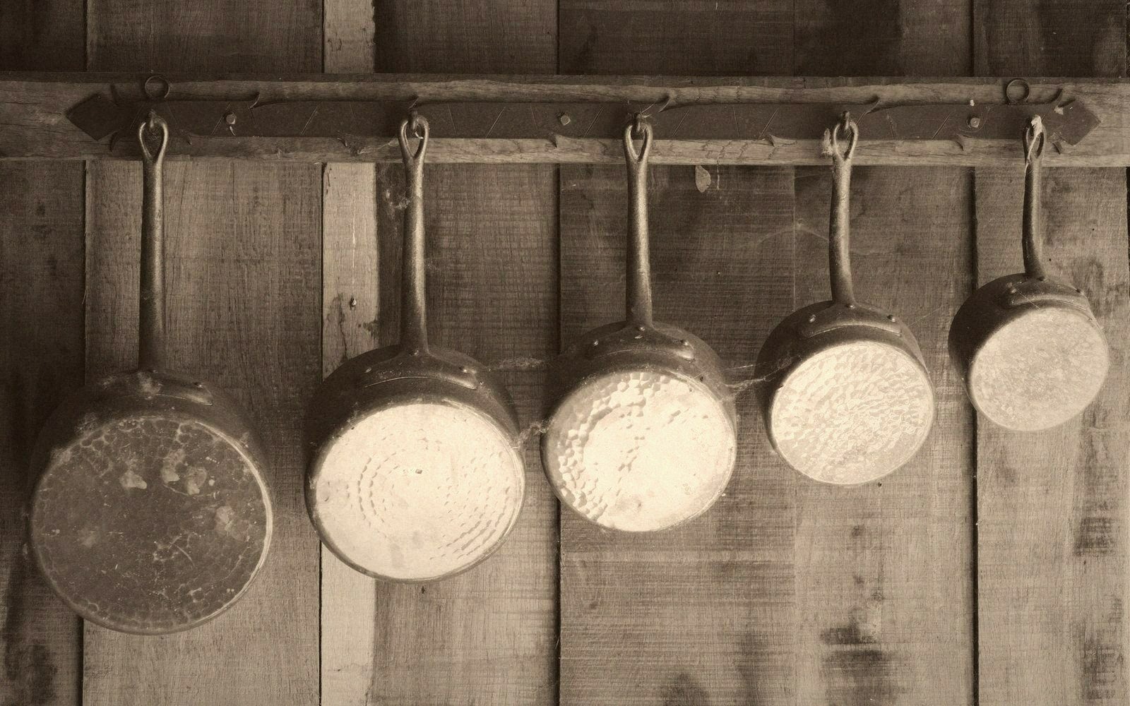 Worn copper pans hanging on a kitchen wall