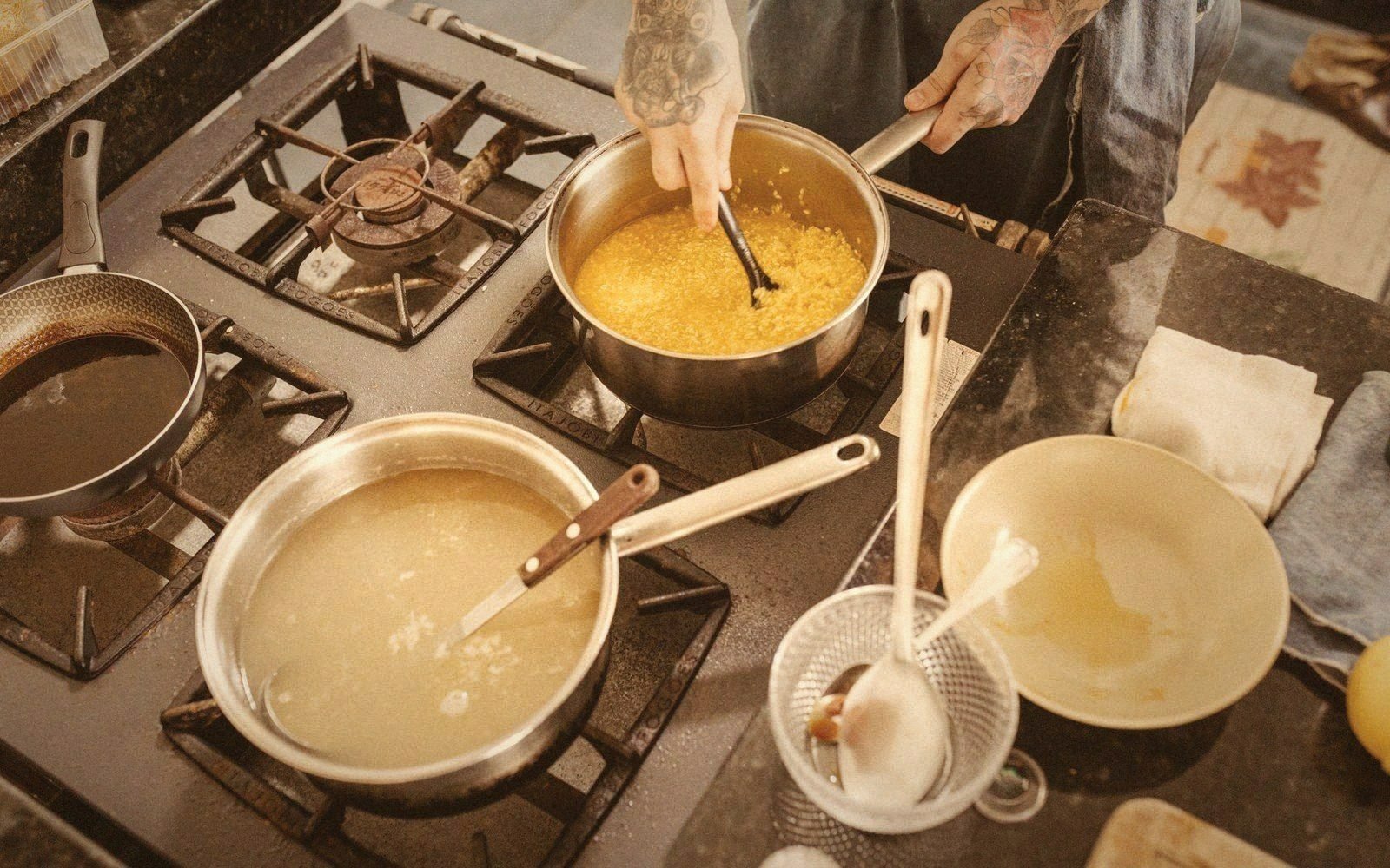 A cook skimming a stockpot at the stove